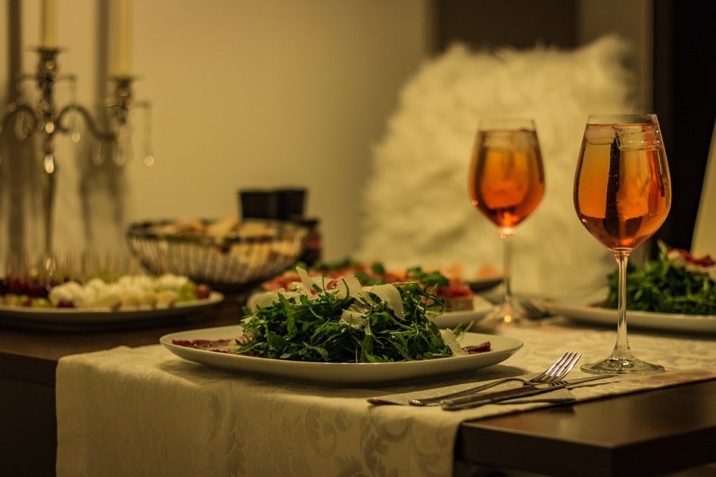 Das Bild zeigt eine festlich gedeckte Tafel mit einem schön angerichteten Teller und mit Weingläsern
