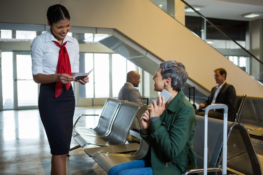Eine Airline-Mitarbeiterin spricht mit einen weiblichen Fluggast